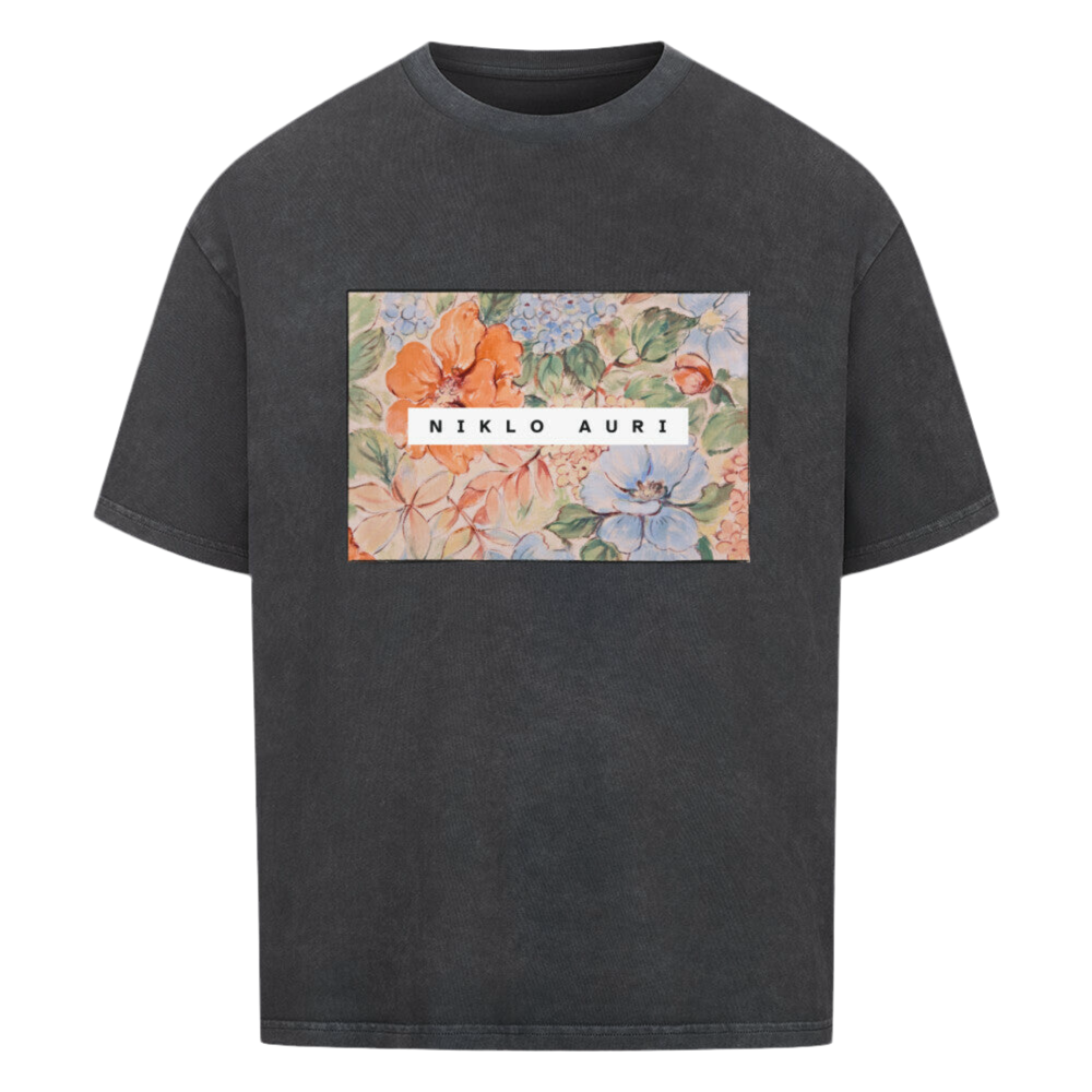 Verwaschenes Schwarzes T-Shirt mit rechteckigem floralen Aquarell-Print und weißem „NIKLO AURI“-Schriftzug zentriert im Motiv.