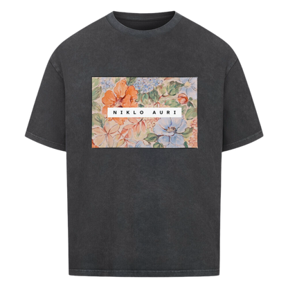 Verwaschenes Schwarzes T-Shirt mit rechteckigem floralen Aquarell-Print und weißem „NIKLO AURI“-Schriftzug zentriert im Motiv.