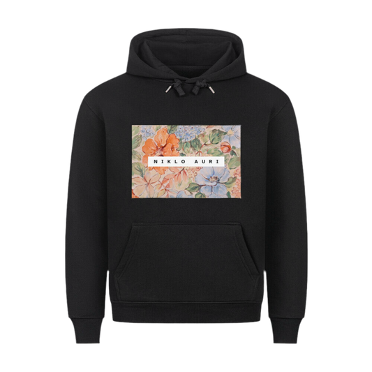 Schwarzer Hoodie mit floraler Aquarellgrafik im Rechteckformat und mittigem „NIKLO AURI“-Schriftzug in Weiß.
