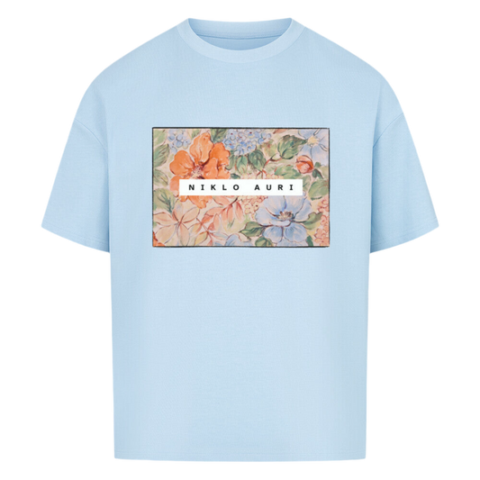 Hellblaues T-Shirt mit rechteckigem floralen Print in Aquarell-Optik und „NIKLO AURI“-Schriftzug in Weiß.