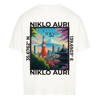 Naturweißes T-Shirt mit farbigem Tokyo-Print auf dem Rücken, eingerahmt von „NIKLO AURI“ und Koordinaten (35.6762° N, 139.6503° E); vorne kleines „NA“-Logo auf der Brust.