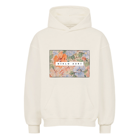 Cremefarbener Hoodie mit rechteckigem Blumenprint in Aquarell-Optik und mittigem weißen „NIKLO AURI“-Schriftzug.