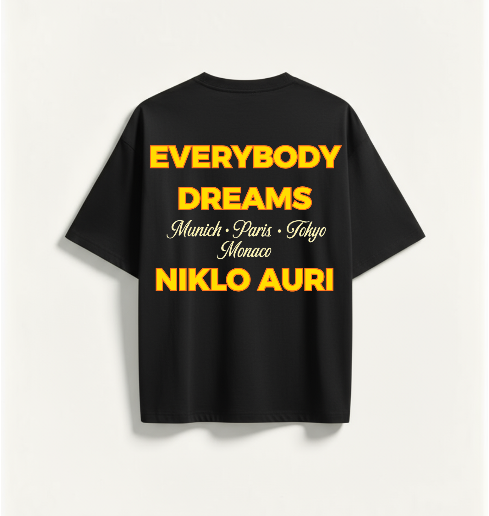„Niklo Auri Everybody Dreams Tee – Schwarz mit gelbem Typografie-Backprint.“